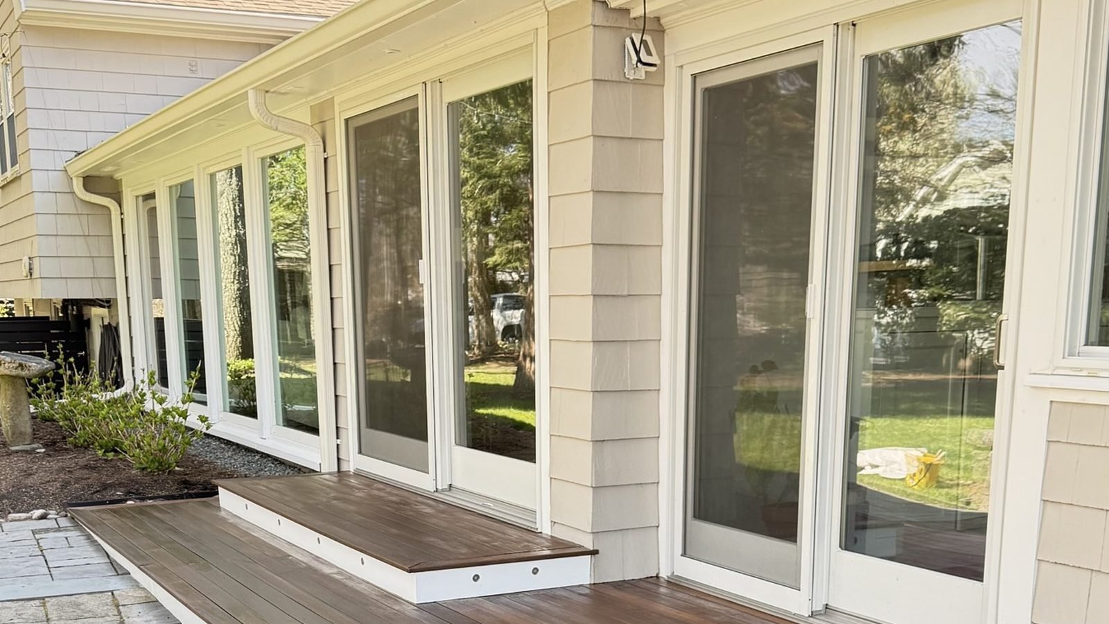 Covered porch with white painted columns, fresh trim and a mahogany deck